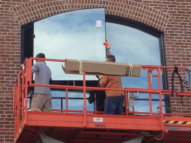 Workers installing large window glass